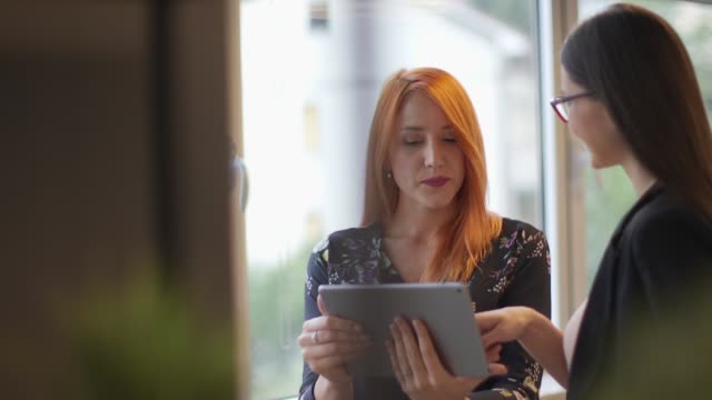 Mujeres-jóvenes-que-trabajan-con-una-tableta-digital-en-la-oficina