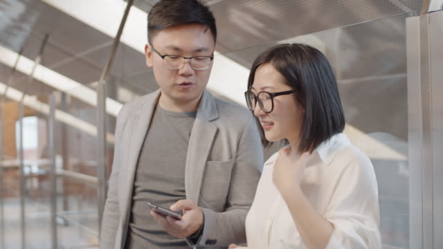 Two-Asian-Businesspeople-with-Cellphone