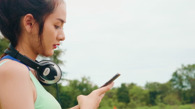 Estilo-de-vida-asiático-deporte-mujeres-sosteniendo-teléfono-inteligente-reproducir-música-relajación