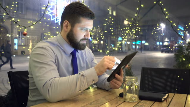 Businessman-browsing-tablet-computer,-evening,-cafe,-slider-dolly-shot