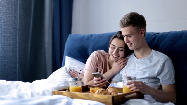 Cheerful-couple-enjoying-romantic-breakfast-in-bed
