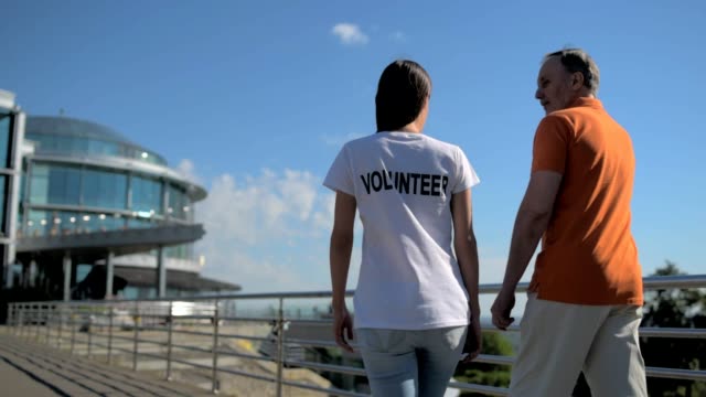 Freiwilligen-zu-Fuß-mit-einem-älteren-Mann-hilfreich-weiblich