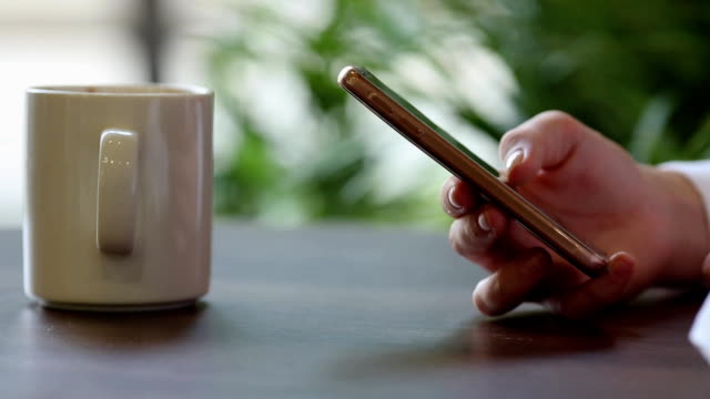 Close-Up-of-Woman's-Hands-Using-Mobile-Phone-at-Coffee-Break