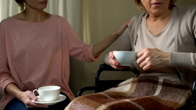 Daughter-trying-to-persuade-mom-to-go-to-nursing-home,-sitting-over-cup-of-tea