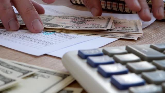 Man-rake-up-dollar-banknotes-on-an-office-desk.-Accounting-or-savings-concept.