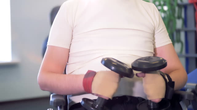 Hübscher-behinderten-Mann-im-Rollstuhl-in-ein-Fitness-Studio-trainiert.
