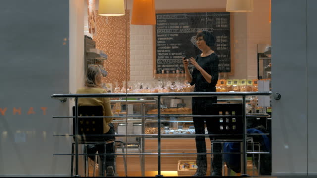 Mujer-con-celular-haciendo-fotos-del-amigo-durante-la-reunión-en-la-cafetería