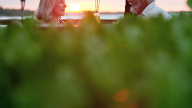 Kaukasische-Senioren-mit-Abendessen-bei-Sonnenuntergang-am-Strandhotel