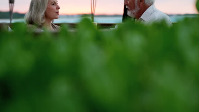Caucasian-seniors-dining-at-sunset-at-beachfront-hotel