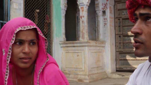 Pan-Nahaufnahme-von-ein-gut-aussehender-Mann-mit-rotem-Turban,-eine-hübsche-Dame-in-Rosa-Sari-in-Rajasthan,-Indien