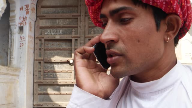 Close-up-of-a-handsome-Indian-man-in-traditional-clothing-talking-on-the-smart-phone-cell-happy