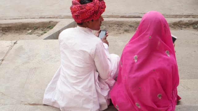 Pareja-de-ropas-tradicionales-en-Pushkar,-Rajasthan,-India-compartir-cuidado-amor-teléfono-celular-móvil