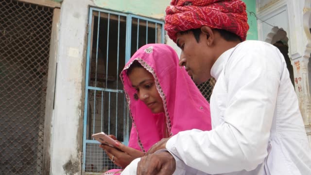 Hermosa-pareja-compartir-chistes-noticias-en-un-pantalla-táctil-móvil-en-Rajasthan-India