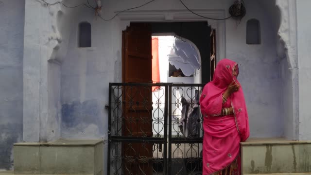 Schöne-Frau-in-Rosa-Saree-warten-auf-ihren-Mann-auf-einer-Straße-in-Pushkar,-Rajasthan,-Indien