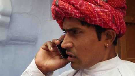 Gut-aussehend-dapper-Cool-indischer-Mann-in-traditionellen-Rajasthani-Verschleiß-und-roten-Turban-auf-seinem-Handy-beschäftigt