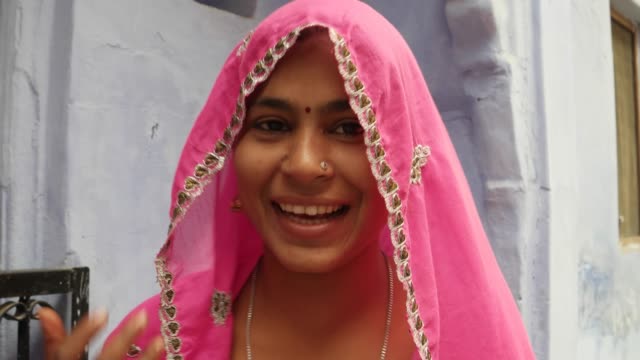 Cerrar-apuesto-alegría-sonriente-feliz-por-una-mujer-bonita-y-con-un-vestido-indio-tradicional-rosa,-hablando-a-la-cámara
