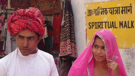 Neigung-bis-zu-indischen-Paar-in-der-Heiligen-Stadt-kaufen-Farbpulver-trocknen-für-Holi-und-Puja-und-Gebet-Orange-rot-rosa