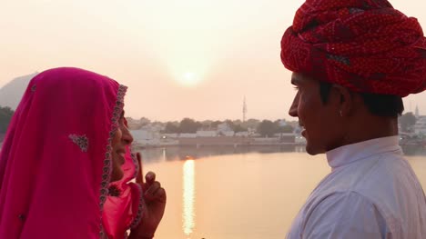 Marido-y-mujer-hablando-contra-la-hermosa-puesta-de-sol-en-el-lago-de-Pushkar,-India,-mano