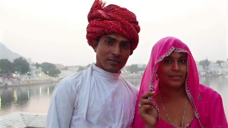 Portrait-of-Indian-husband-with-turban-and--lovely-wife-in-sari-in-front-of-Pushkar-Lake,-Rajasthan,-India