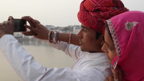 India-pareja-teniendo-hermosa-puesta-de-sol-cámara-teléfono-fotos-lago-de-Pushkar,-Rajastán