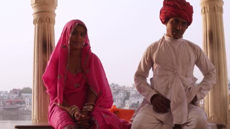 Hermosa-pareja-indio-en-traje-tradicional-sentado-con-el-lago-de-Pushkar-en-el-fondo,-Rajasthan,-India