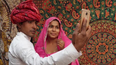 Vestidos-de-tiro-mano-de-pareja-tradicional-de-la-India-tomando-un-selfie-en-una-cámara-de-teléfono-móvil-en-Pushkar,-Rajastán