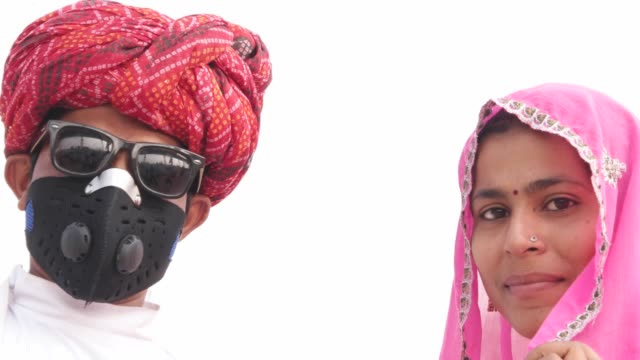 Rajasthani-hombre-con-una-máscara-de-contaminación-y-gafas-de-sol-con-su-esposa-en-la-Feria-de-Pushkar,-India