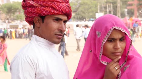 Pan-to-beautiful-Indian-couple-in-traditional-clothing-at-the-busy-fairgrounds-of-Pushkar-Fair,-India
