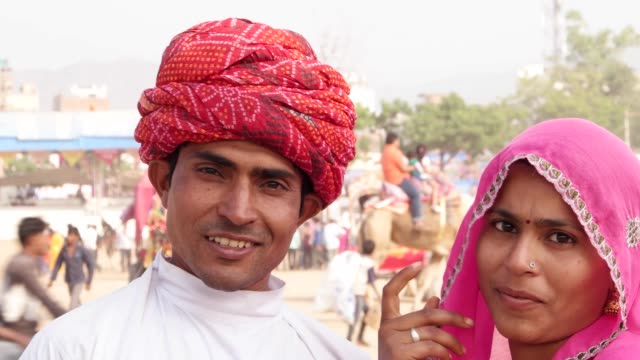 Tilt-up-to-portrait-of-beautiful-Indian-couple-in-traditional-clothing-at-the-busy-fairgrounds-of-Pushkar-Fair,-India