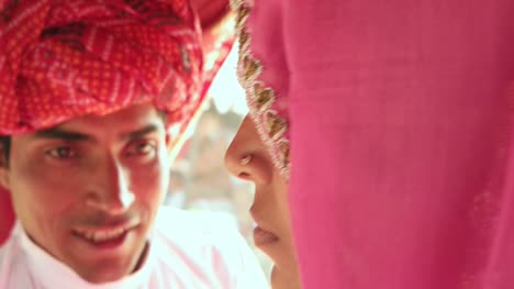 Nahaufnahme-von-Rajasthani-Paar-in-ethnischen-Kleid-genießen-einen-Kamelritt-in-einem-Wohnwagen-in-Pushkar-Fair
