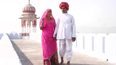 Gran-tiro-de-guapo-masculino-y-hermosa-mujer-caminar-con-confianza-hacia-la-cámara-en-un-tejado-en-Rajasthan,-India