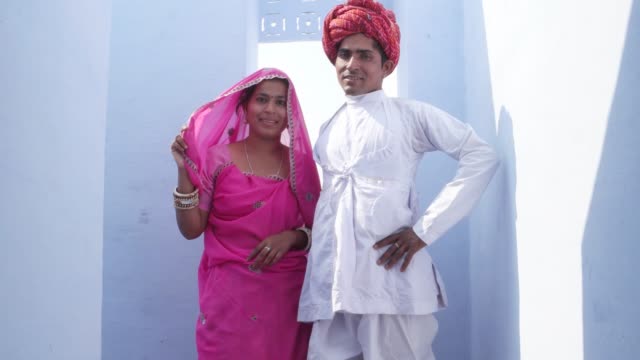 Mujer-en-sari-rosa-camina-hasta-un-hombre-de-turbante-rojo-y-blanco-kurta-y-pose-para-la-cámara-en-Rajasthan,-India