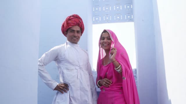Cambio-de-enfoque-a-una-hermosa-novia-tradicional-y-el-novio-en-ropa-tradicional-contra-un-fondo-azul-en-la-India