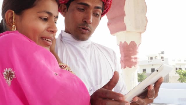 Esposa-India-tradicional-y-esposo-trabajo-enseñanza-aprendizaje-en-un-tablet-en-Rajasthan,-India