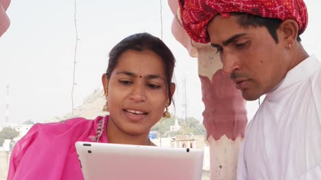 Rajasthani-paar-arbeiten-lernen-Lehren-Teilen-auf-einem-Tablett-tragen-Rosa-Sari-und-roten-Turban-in-Indien