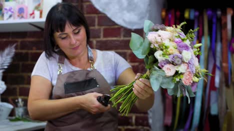 professionellen-Floristen-schneiden-Blume-ergibt-sich-mit-einer-Schere-in-Hochzeitsstrauß-im-floralen-Designstudio