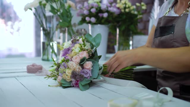 professionellen-Floristen-arrangieren-mit-Band-Hochzeit-Blumenstrauß-im-floralen-Designstudio