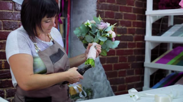 professionellen-Floristen-schneiden-Blume-ergibt-sich-mit-einer-Schere-in-Hochzeitsstrauß-im-floralen-Designstudio