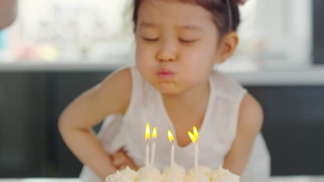 Adorable-chica-asiática-soplar-velas-sobre-el-pastel