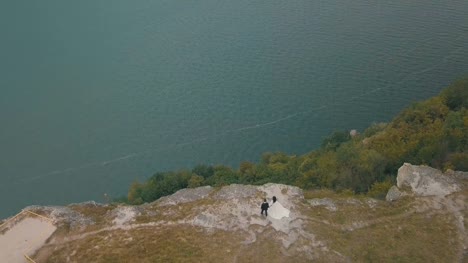 Young-and-beautiful-wedding-couple-together-on-the-slope-of-the-mountain-near-sea.-Lovely-groom-and-bride.-Shooting-from-the-air.-Aerial-shot