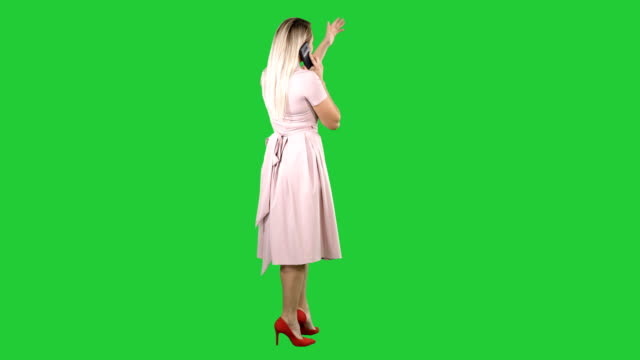 Standing-young-beautiful-girl-making-a-call-on-a-Green-Screen,-Chroma-Key