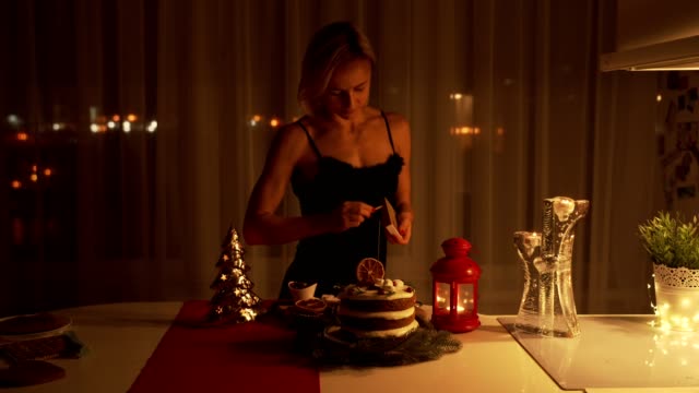 Junge-Frau,-die-Beleuchtung-eine-Wunderkerze-in-den-Kuchen-in-der-Nacht-in-der-Weihnachtszeit