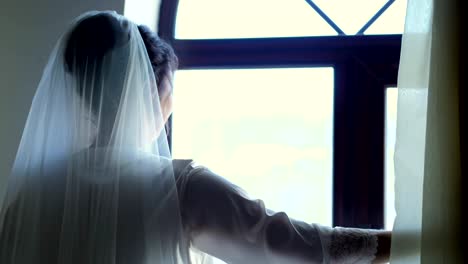Portrait-einer-Braut,-schöne-Mädchen,-Schleier-und-weißen-Frisiermantel,-Robe,-schiebt-die-Vorhänge,-schaut-aus-dem-Fenster