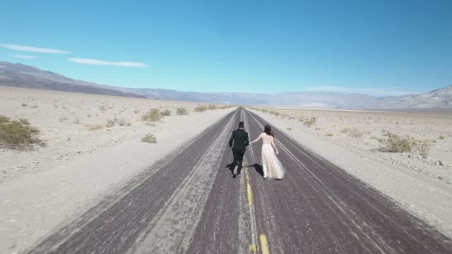 Braut-und-Bräutigam,-die-auf-leere-Wüstenstraße-im-Death-Valley,-USA