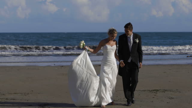 Feliz-pareja-de-recién-casados-caminando-por-la-playa