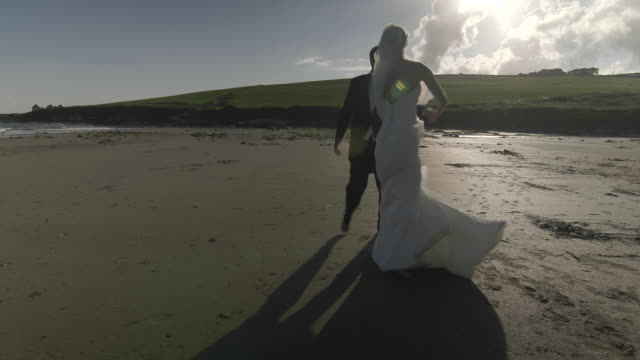 Sonriente-pareja-de-recién-casados-bailando-en-la-playa