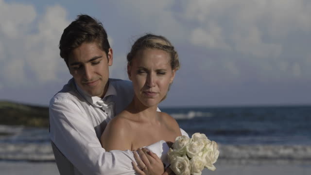 Smiling-newlyweds-hugging-on-the-beach