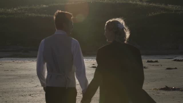 Sonriente-pareja-de-recién-casados-caminando-juntos-en-la-playa