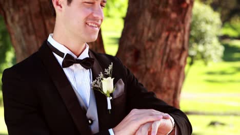 Glückliche-Bräutigam-lächelt-in-die-Kamera-und-überprüfen-seine-Uhr