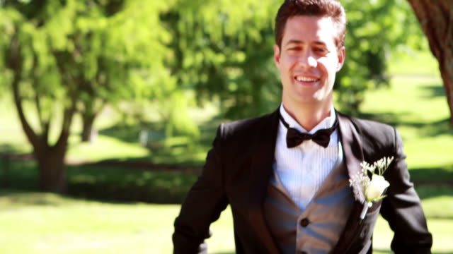 Attractive-groom-walking-towards-and-smiling-at-camera